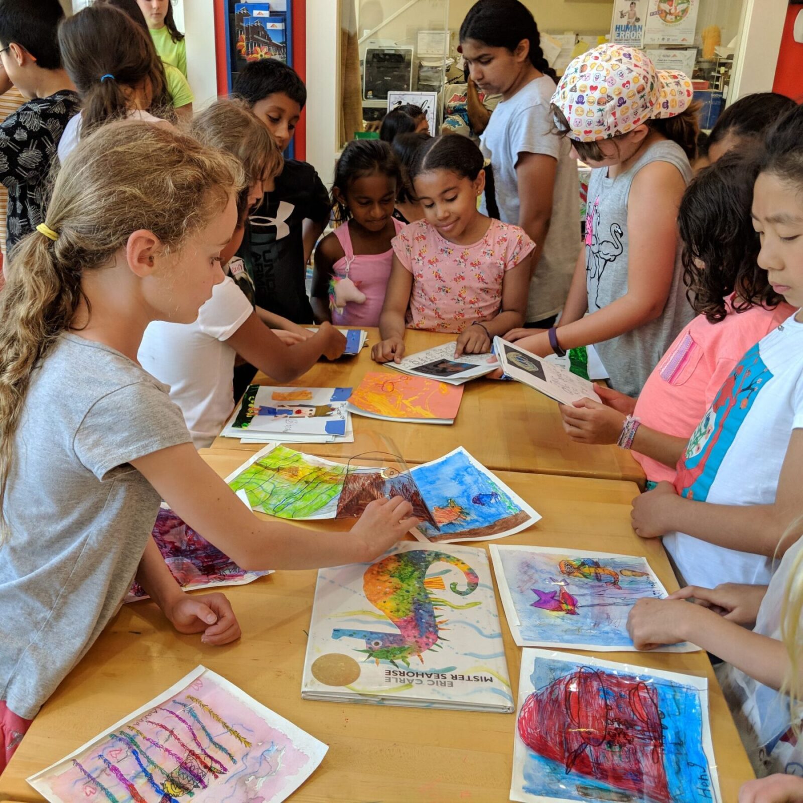 Group of children looking at artwork on a table