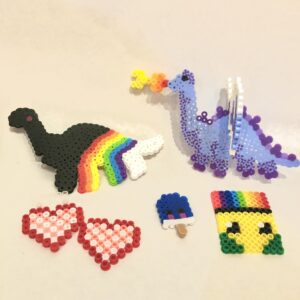 Perler bead projects of rainbow dino, purple dragon, hearts, and popsicles