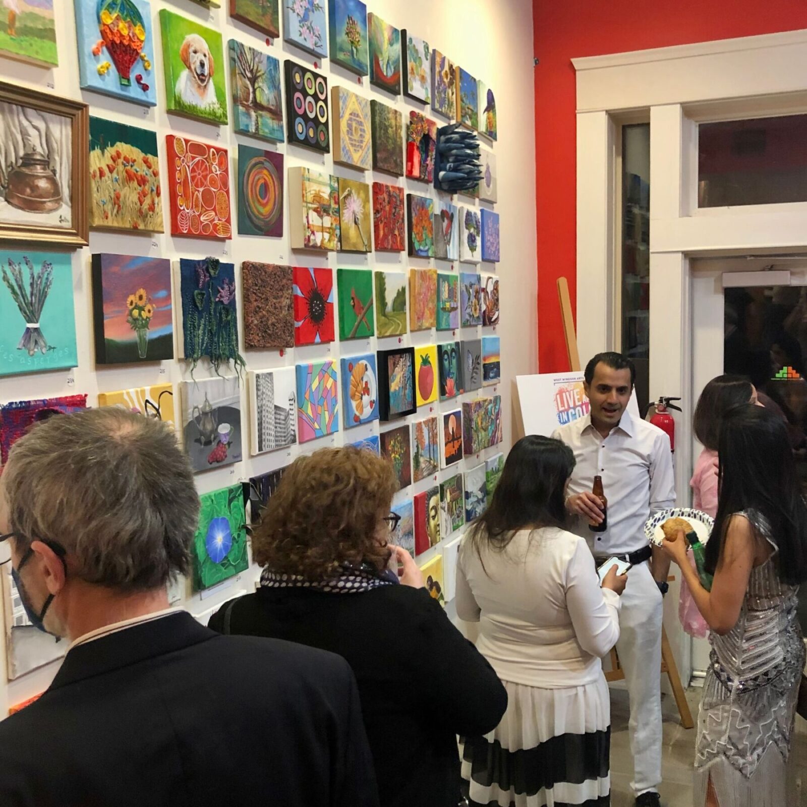 GR8 Works Fundraising Art Show, image of 8x8 works on art on the wall, with people in the foreground