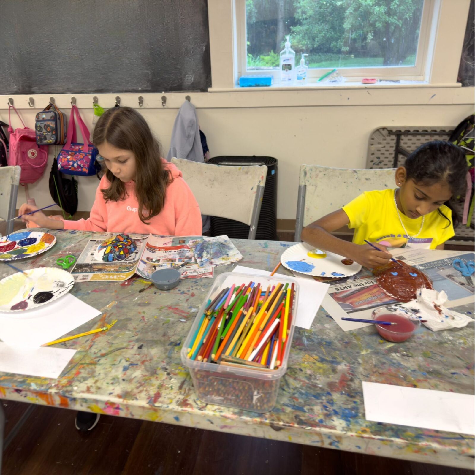 Two girls painting colorful plaster masks