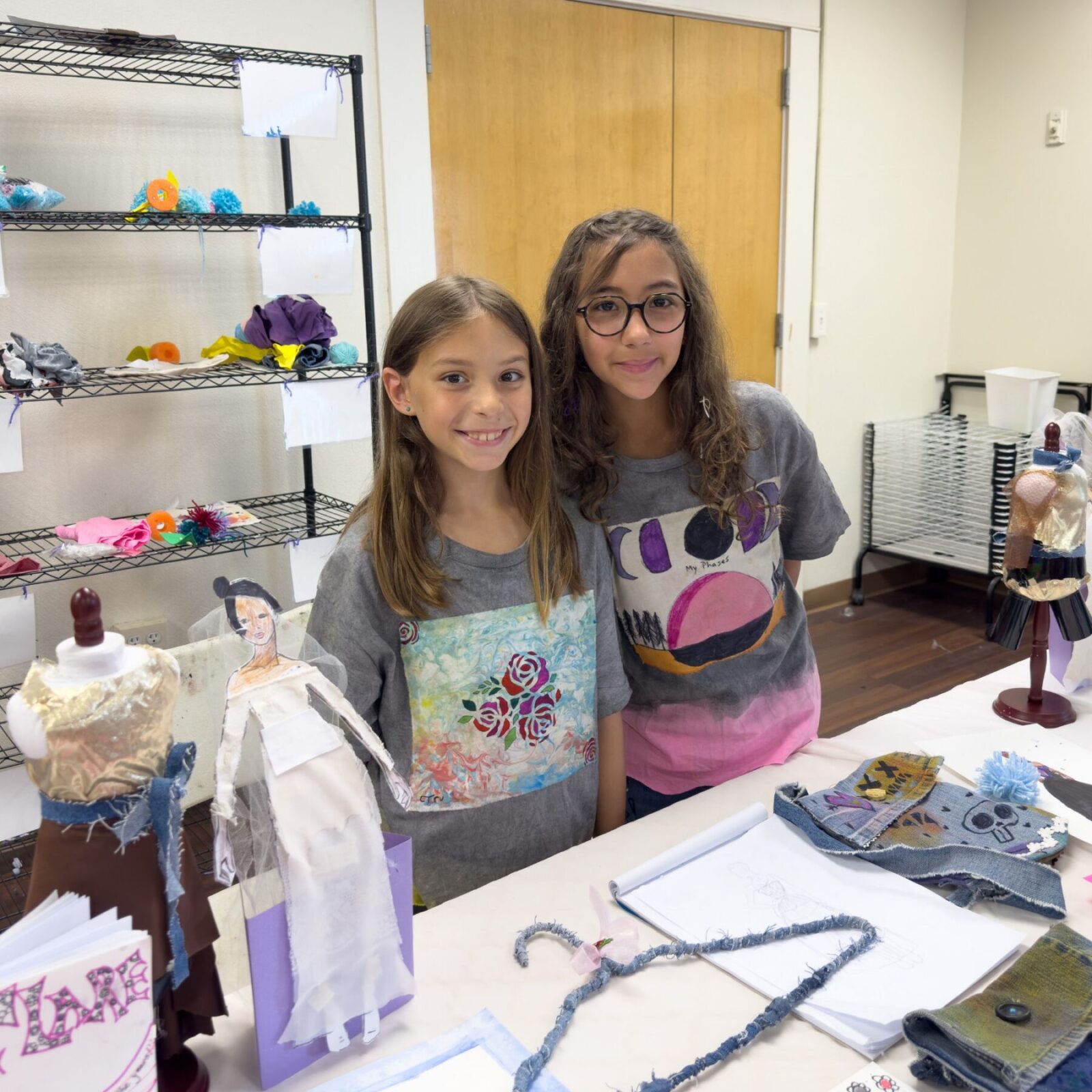 2 girls with their fashion t-shirts they designed and paper fashion dolls