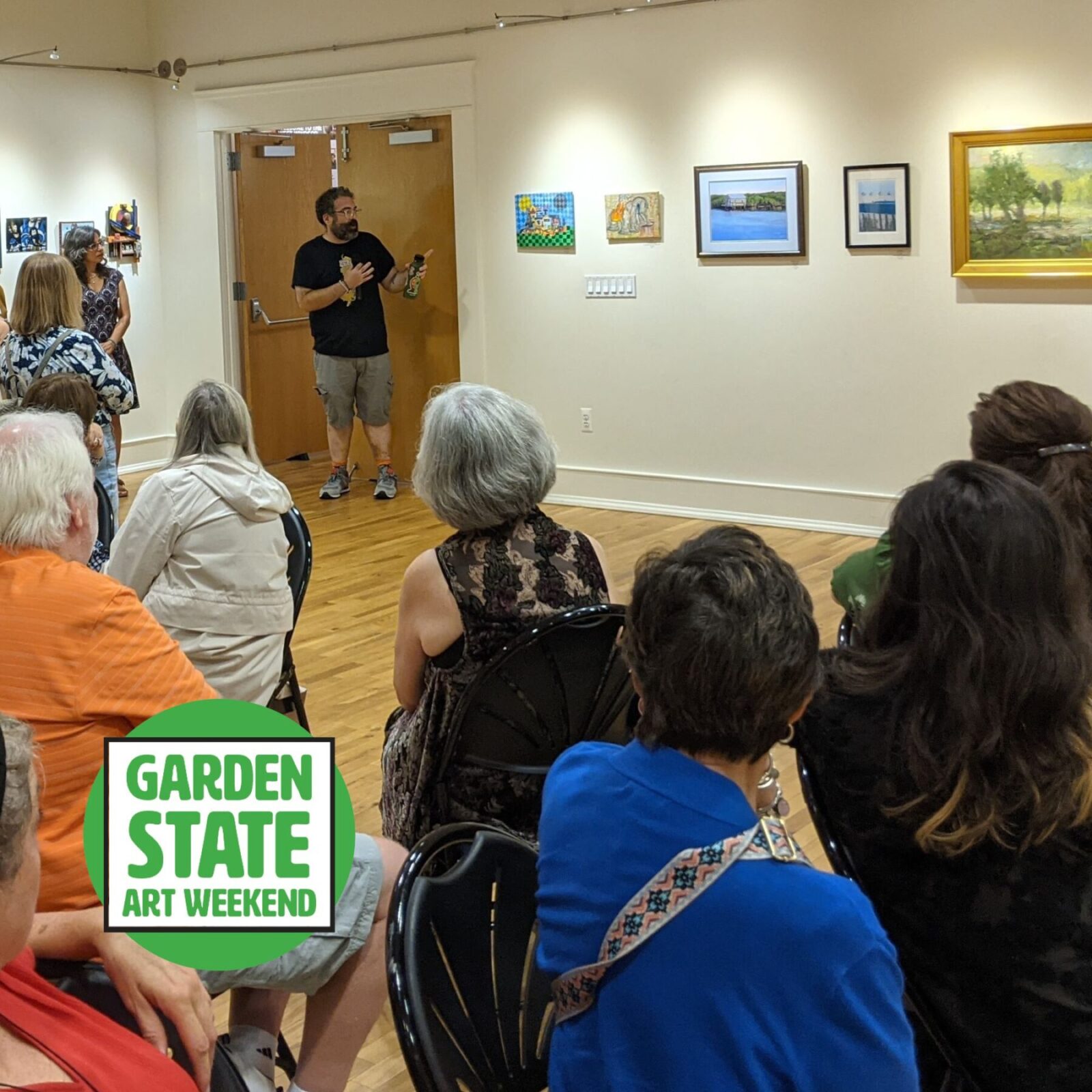 Gallery photo of artist talking to crowd with Garden State Art Weekend Logo