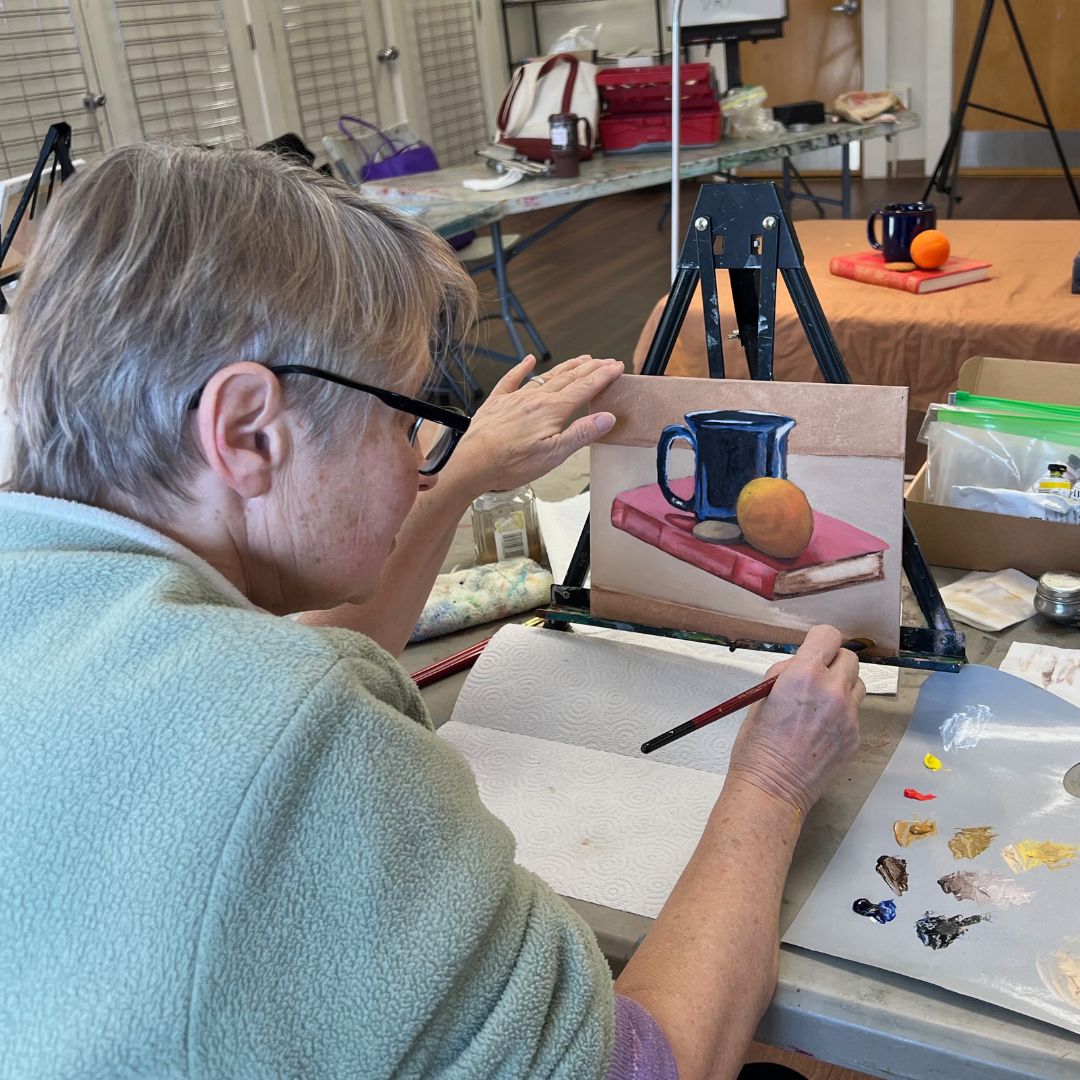 woman paints a still life in oil paint