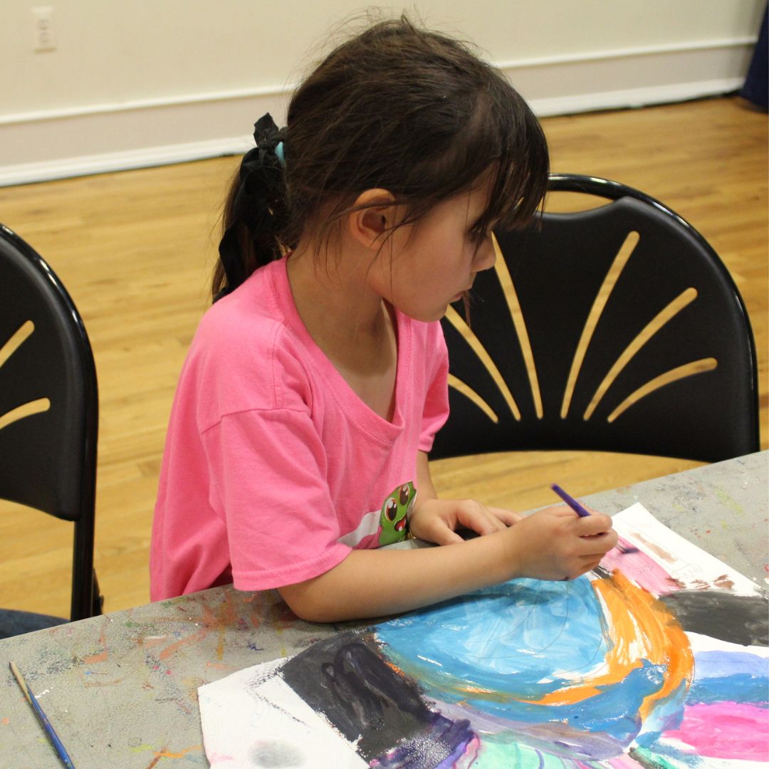 girl in pink shirt painting blue, orange, pink, and black watercolor painting